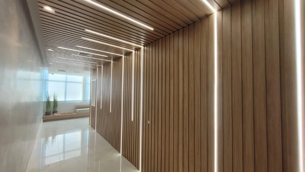 Corredor corporativo com painel ripado e iluminação integrada Verssato